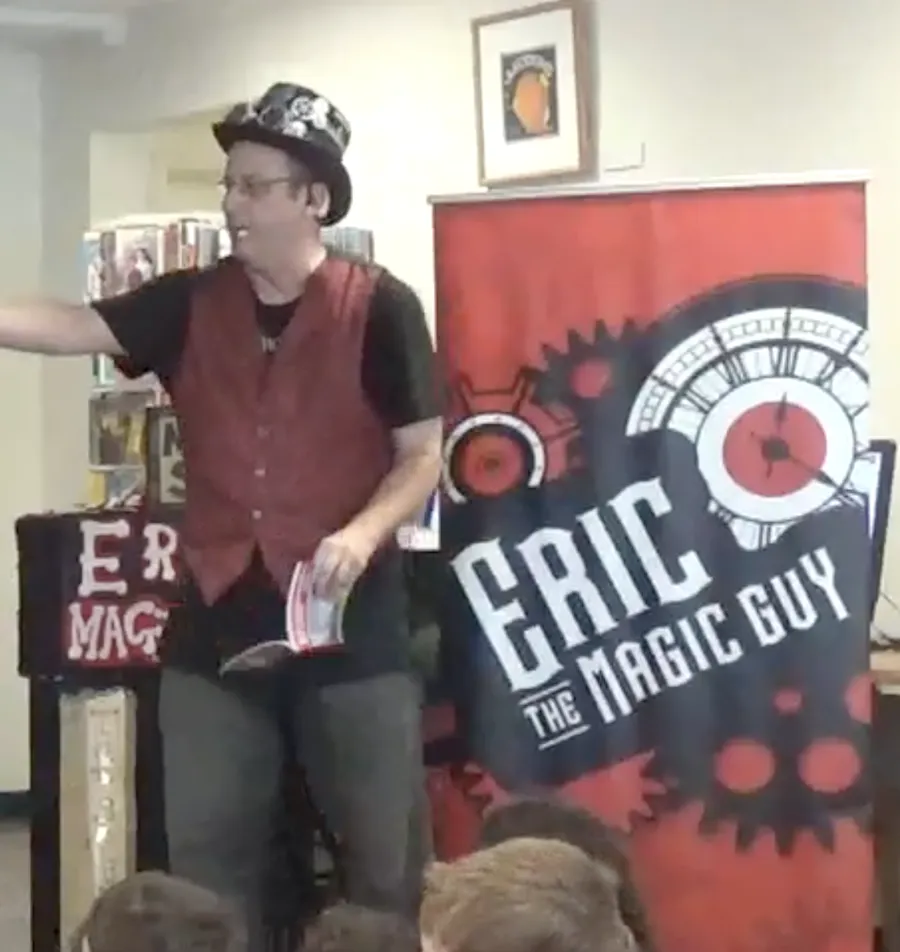 Eric The Magic Guy performing a library show in front of his Eric The Magic Guy banner